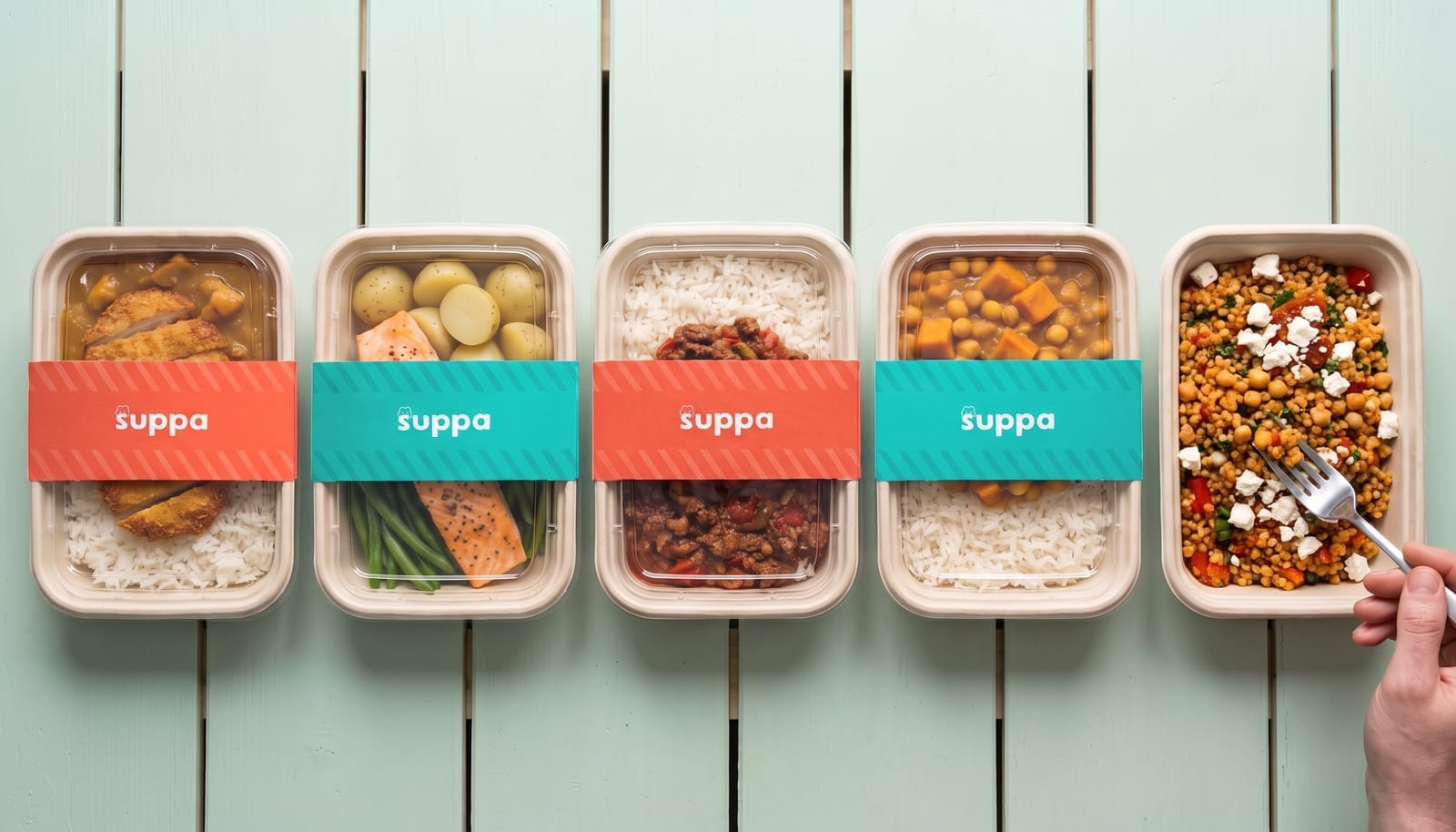 Five open Suppa meal trays on a mint table, with their teal sleeves and lids beside them